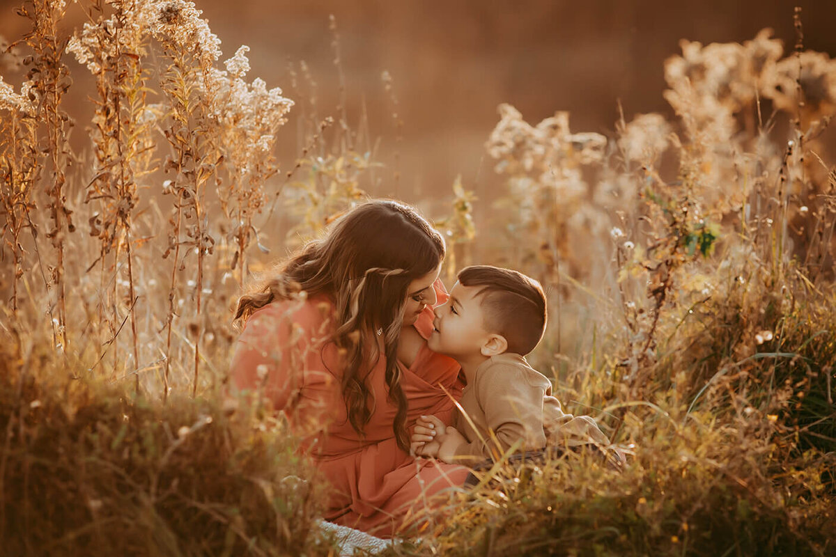 a mother and her son are doing an eskimo kiss in a golden field in rochester, ny