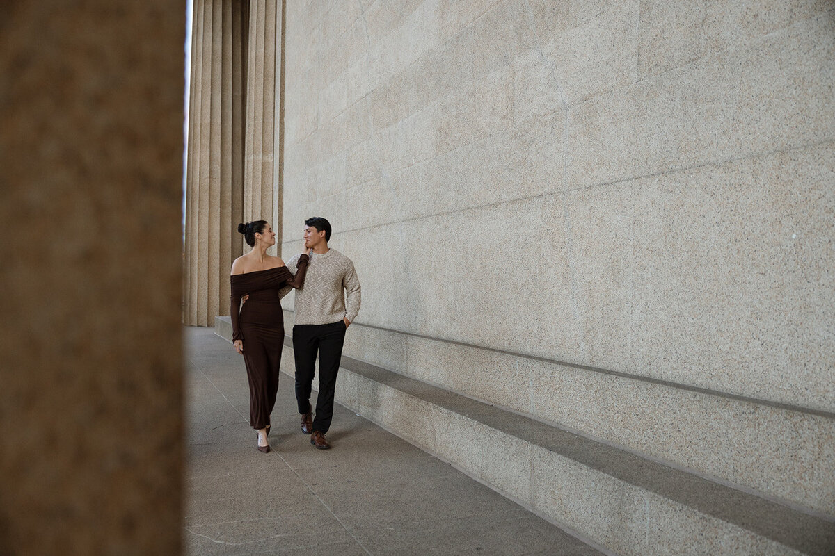Couple walks side-by-side along the pillars at the Parthenon in Nashville, TN. 