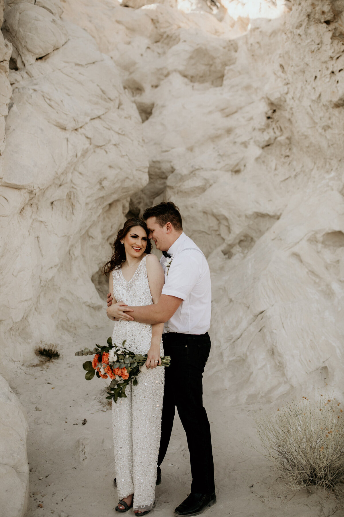 groom hugging bride from behind in a white rock canyon