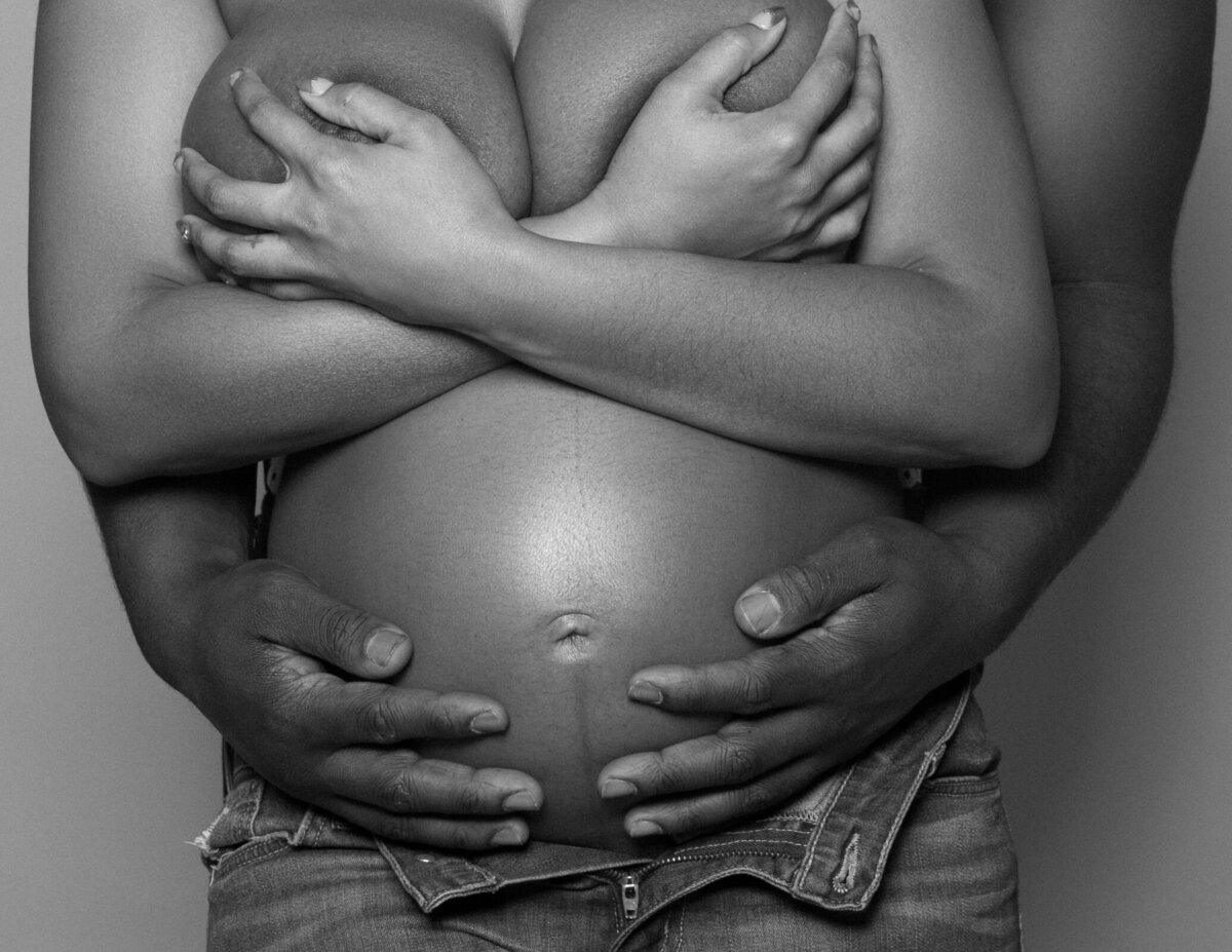 Gorgeous maternity photo of a pregnant woman with her husband holding the belly.