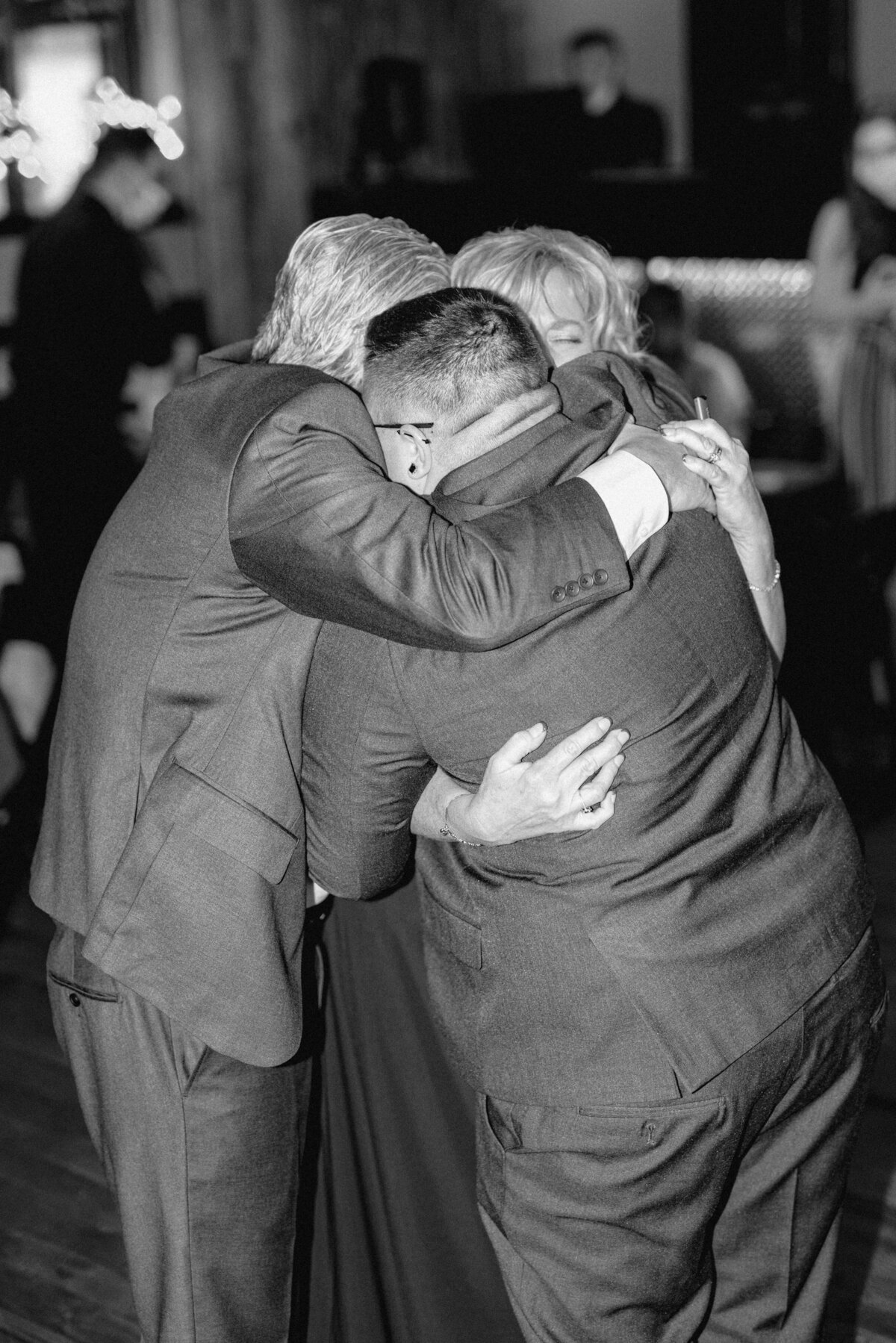 Black and white image of a marier being embraced by their parents