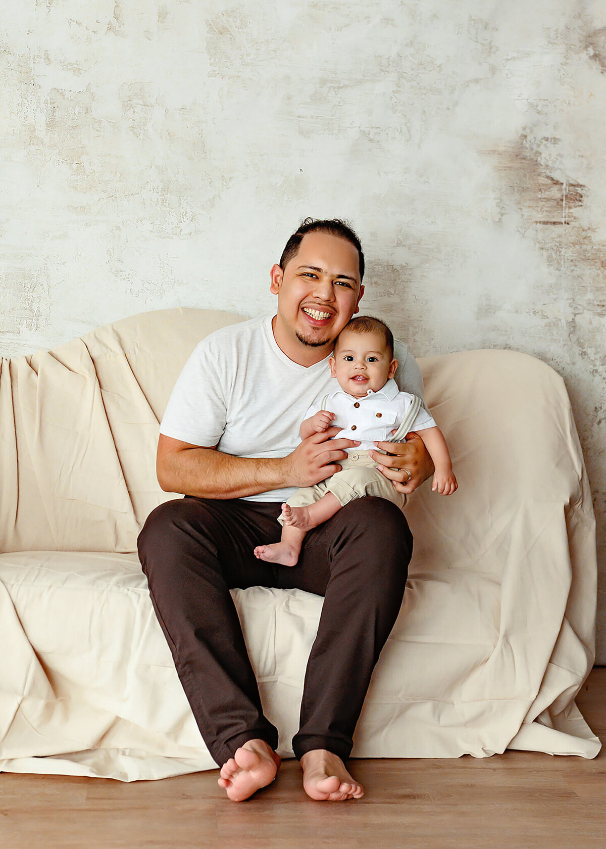portrait of dad and son in a minimalistic setting, canvas covered couch white textured background