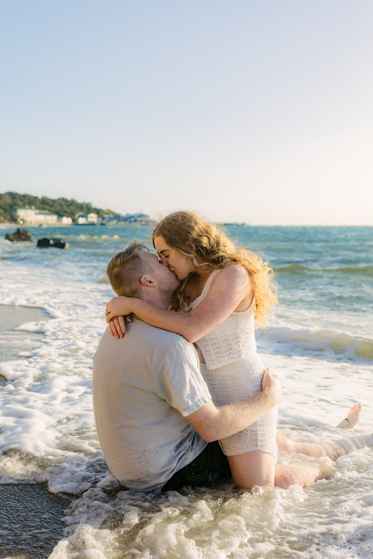 A couple kissing and playing in the waves on the beach in Melbourne. 