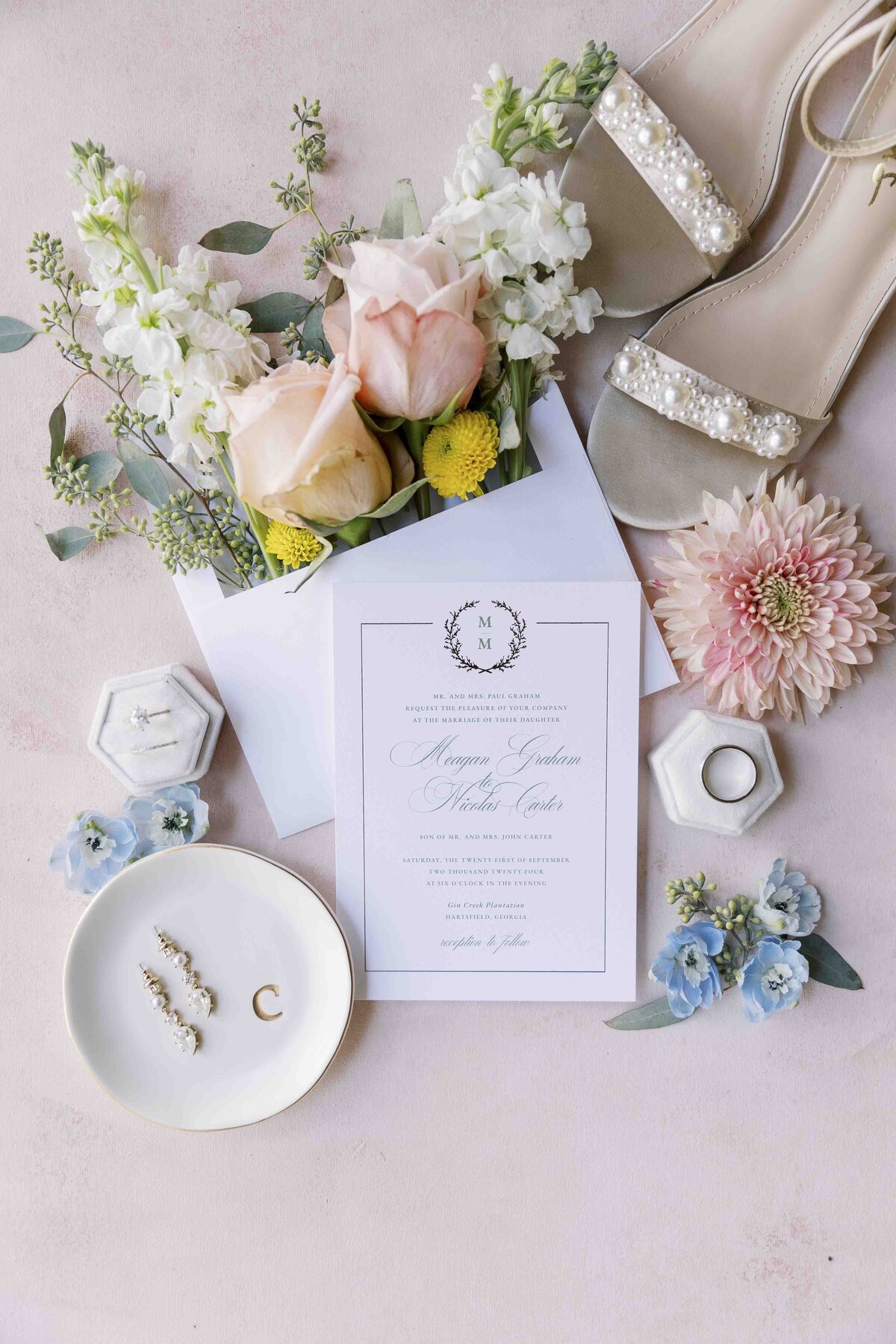 a flat lay including a wedding invitation and colorful flowers