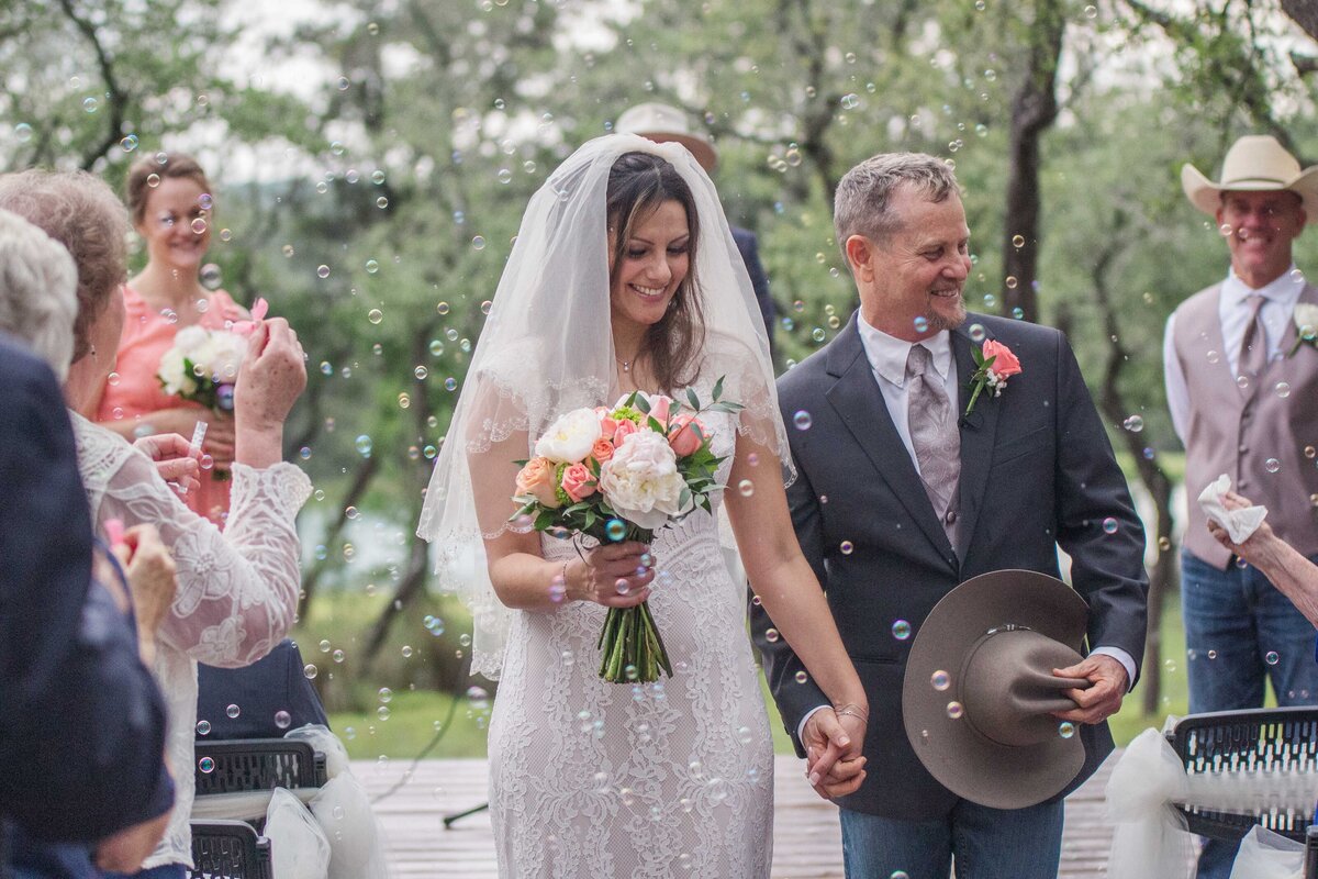 bride and groom return down the aisle through bubbles blown by guests at Boerne Texas wedding