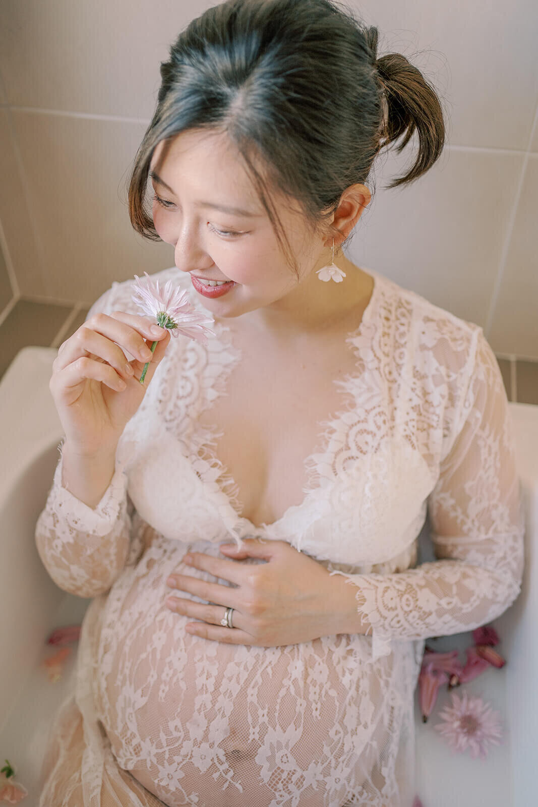 Radiating grace, a Chinese descent mum in a lace white gown captures the magic of pregnancy at a Gold Coast milk bath maternity shoot