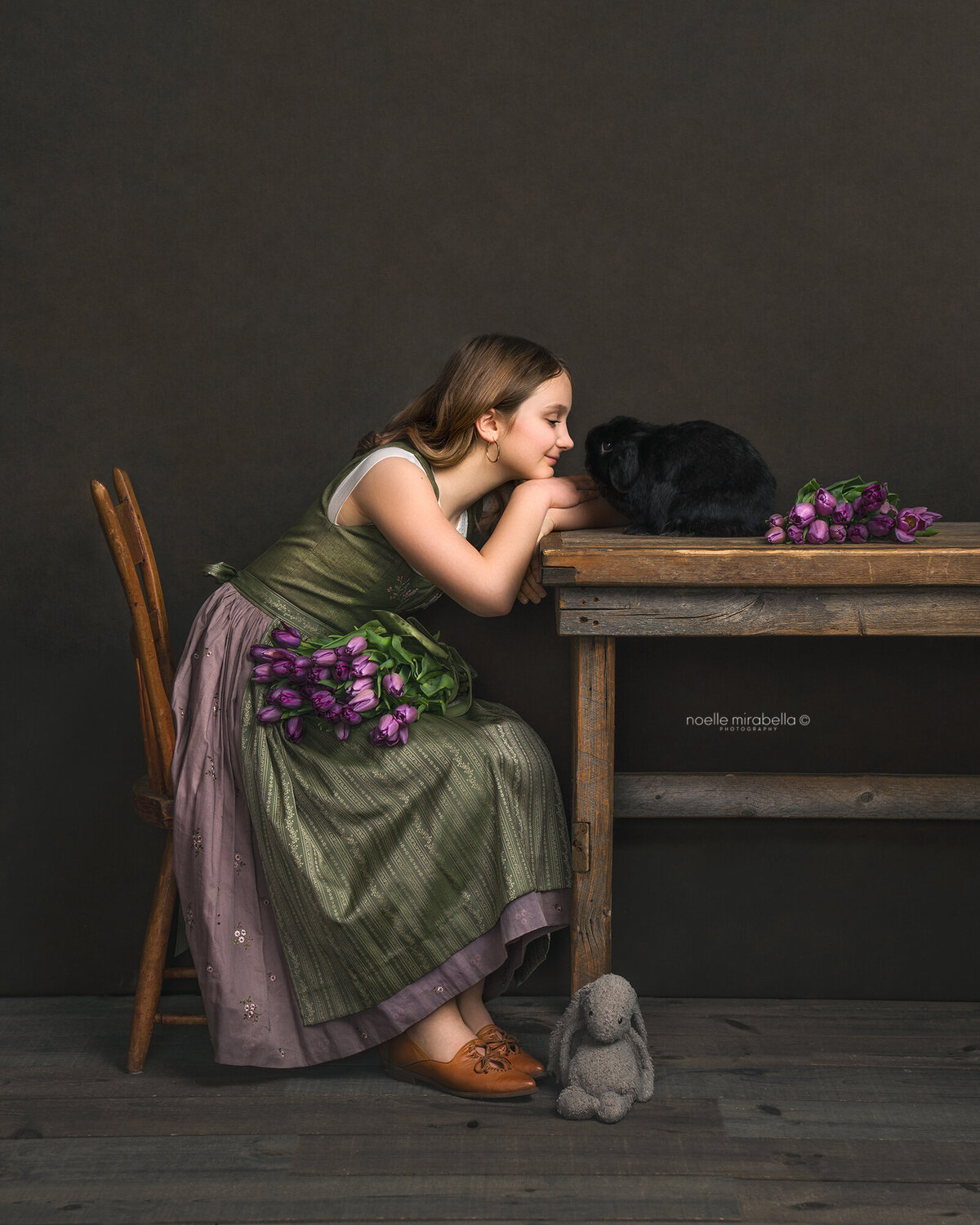 Girl  sitting at a table, touching noses with her bunny.