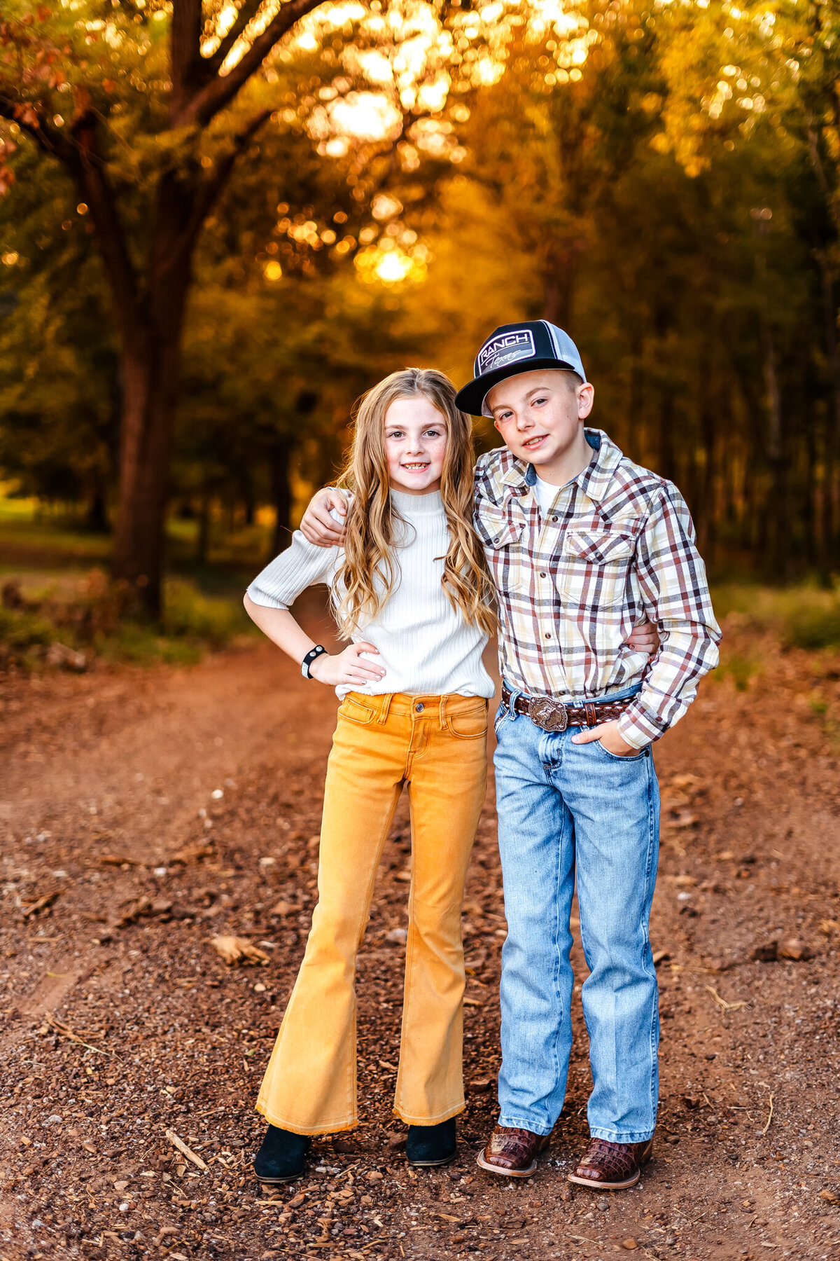 Brother and sister standing  on a dirt road at sunset in Gilmer, Texas