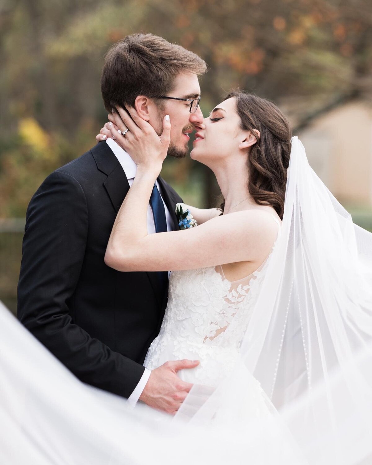 A bride and groom kiss surrounded by her veil