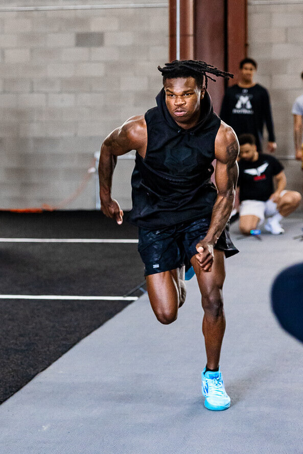 Football star Travis Hunter sprints on an indoor track.