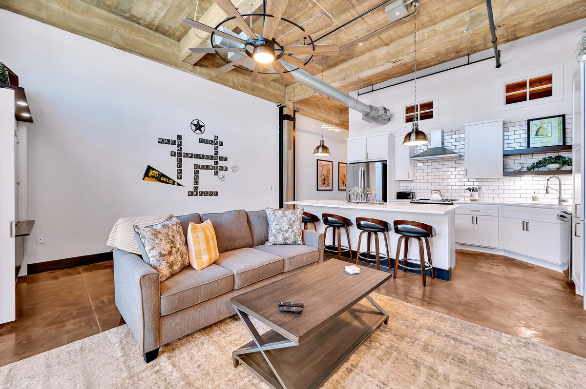 Open concept living room and kitchen in this one-bedroom, one-bathroom vintage condo that sleeps 4 in the historic Behrens building in the heart of the Magnolia Silo District in downtown Waco, TX.