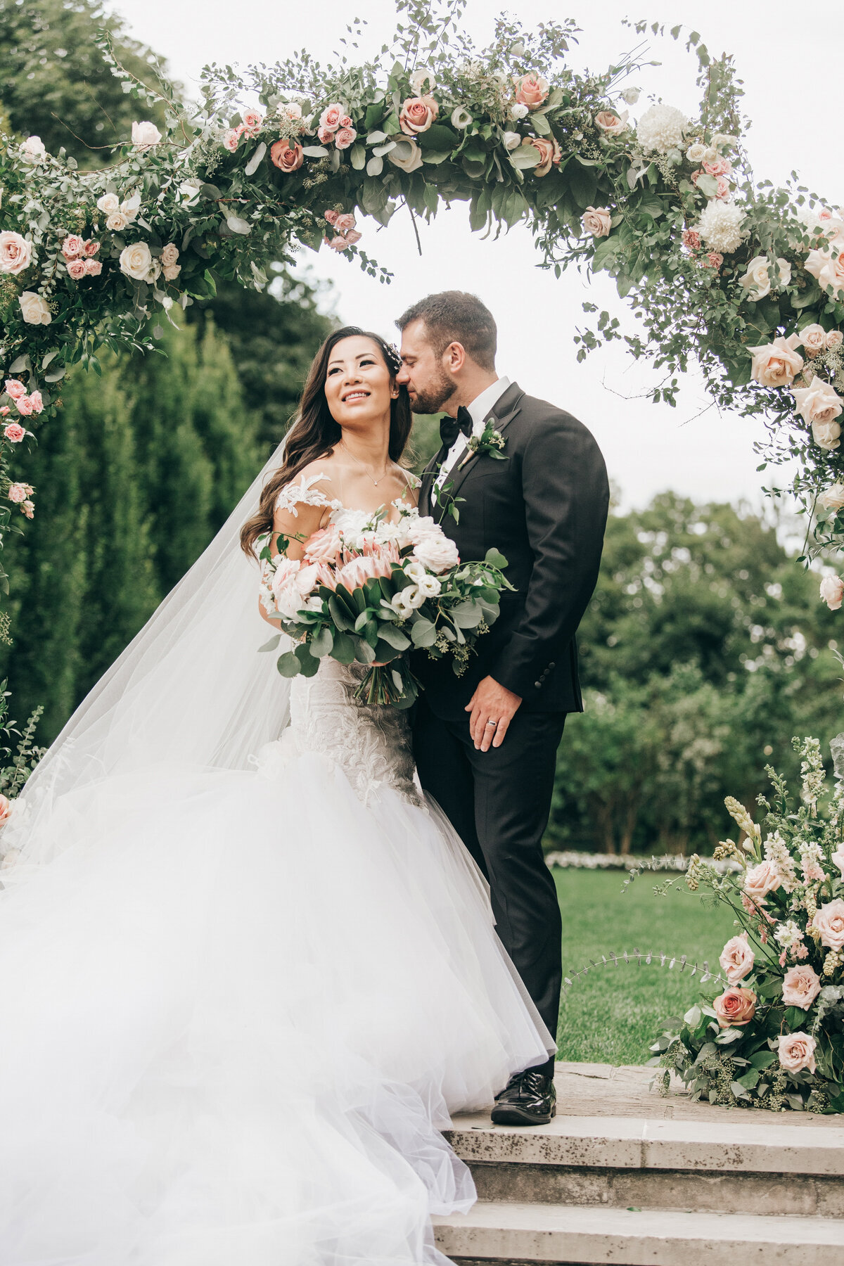Glamorous portraits of bride and groom under floral arch