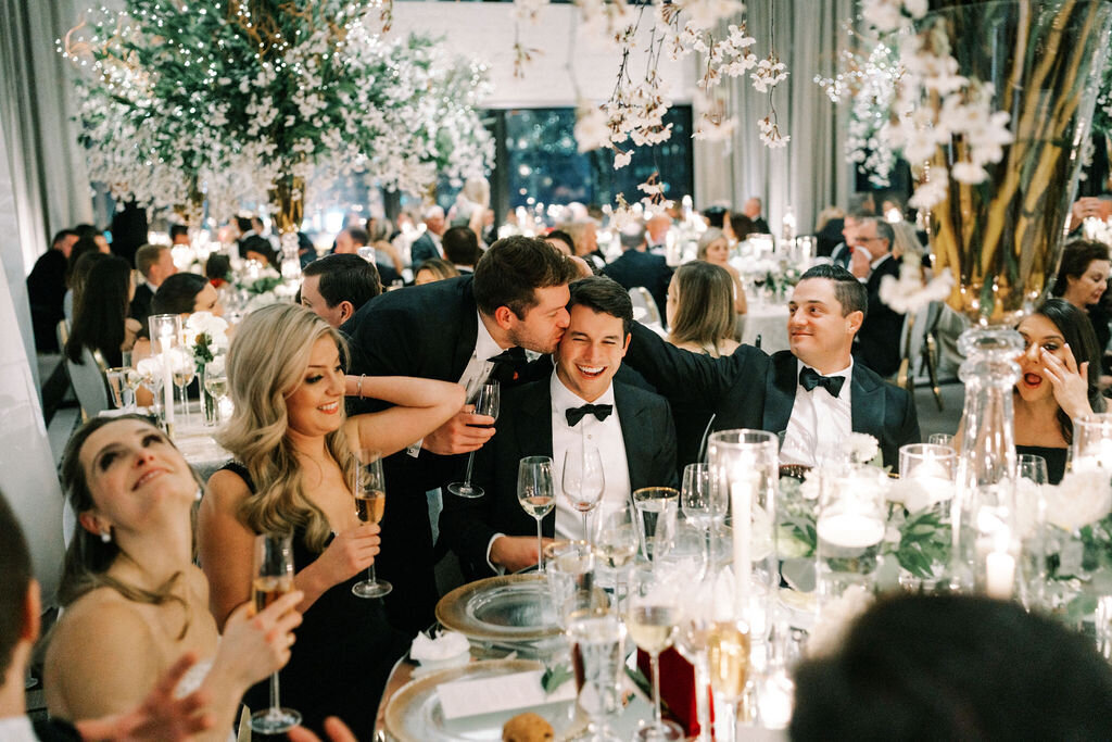 Picture of a wedding guest kissing the groom on the forehead. 