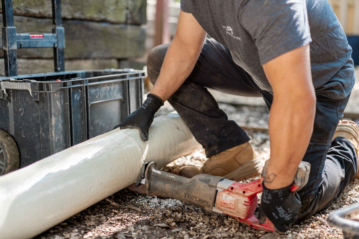 Man knelt down using tools for basement waterproofing Atlanta