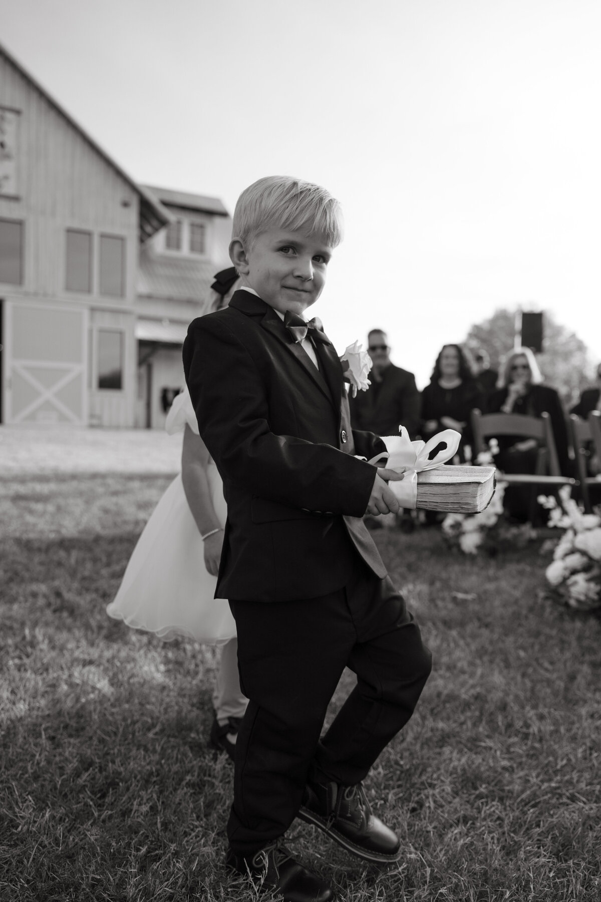 ring bearer smirks carrying wedding rings during ceremony