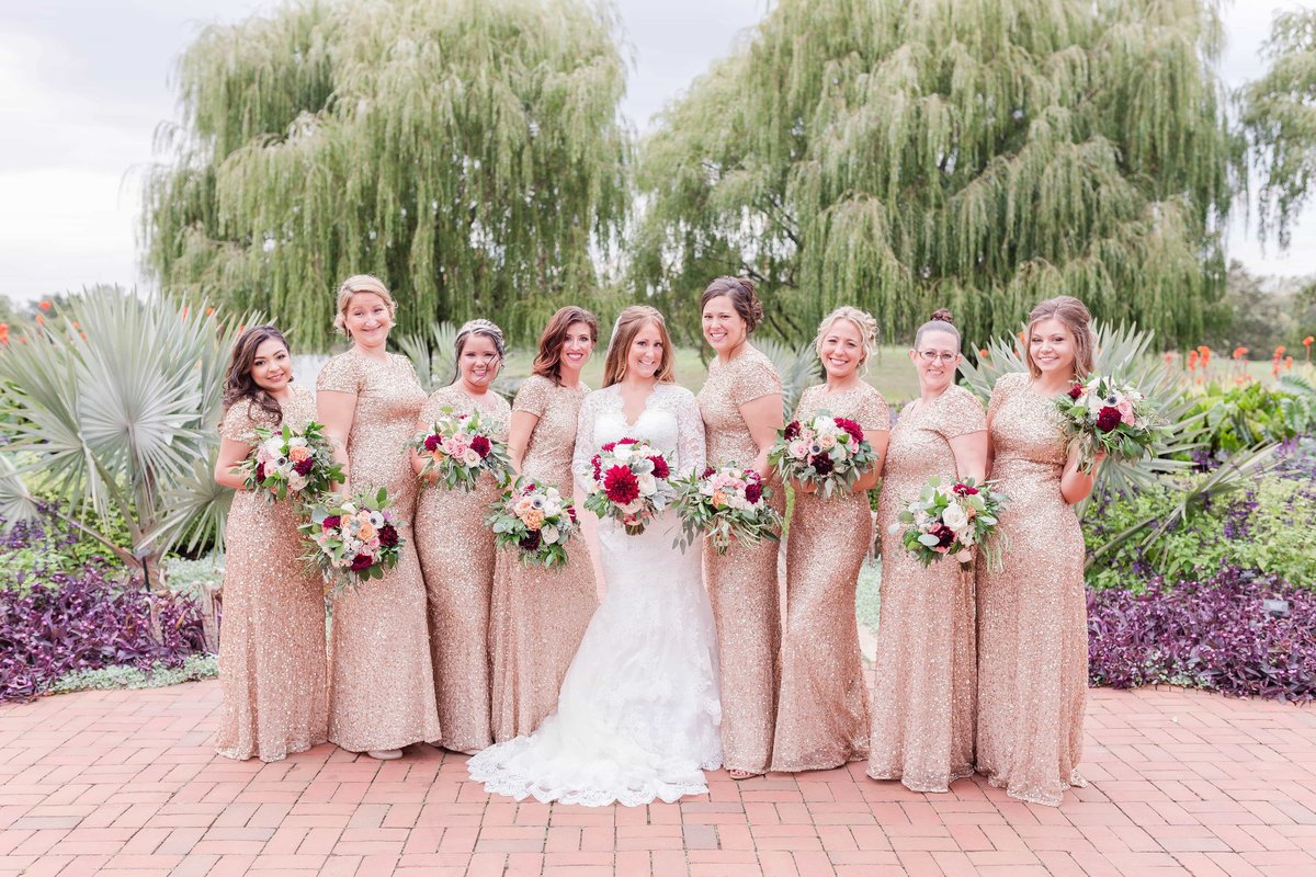Portrait of bride and bridesmaids wearing neutral dresses in front of beautiful willow trees in Chicago.