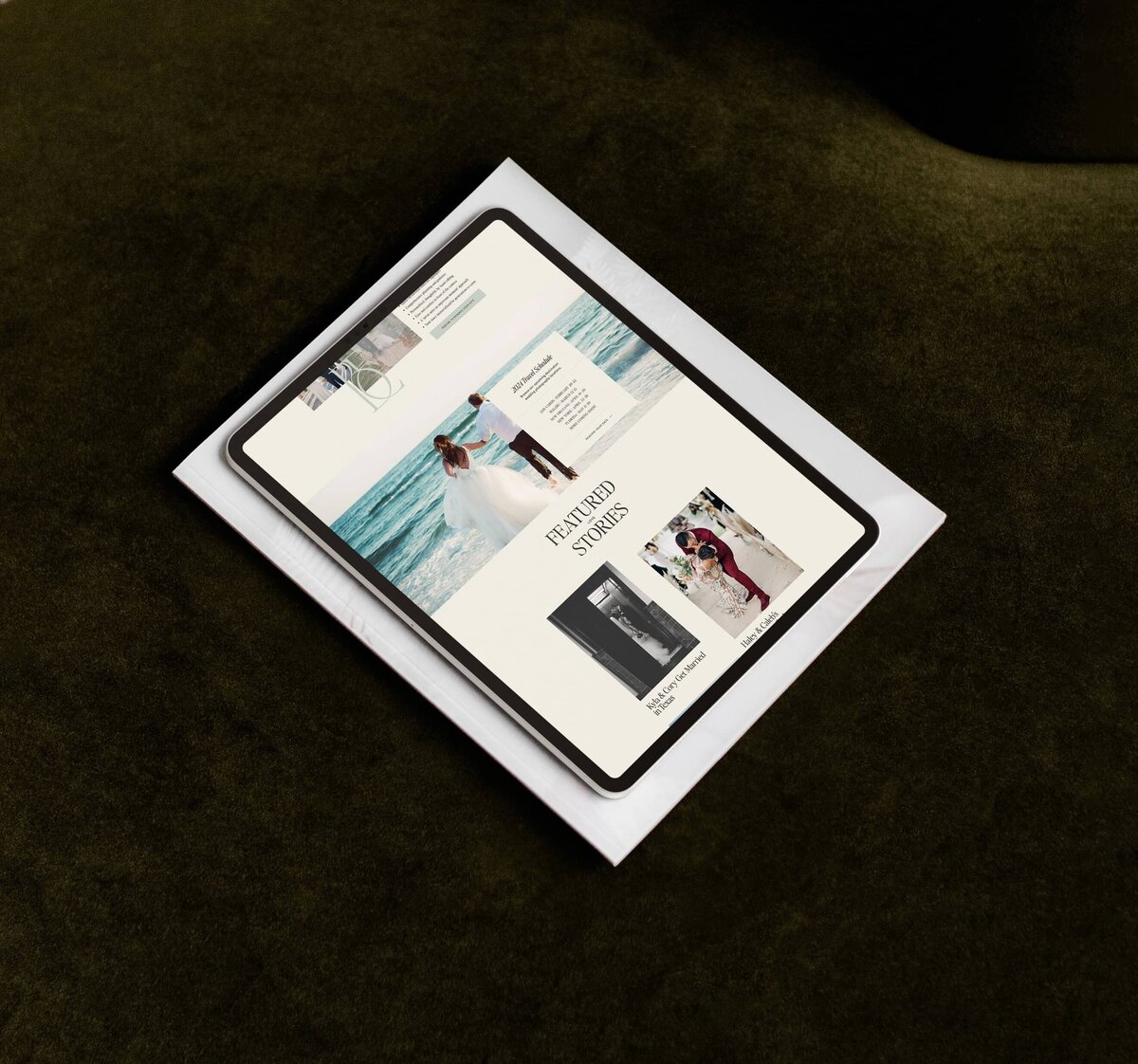 A tablet displaying a website featuring wedding-related content, including custom brand and Showit web design for photographers, rests atop an envelope on a dark green surface.