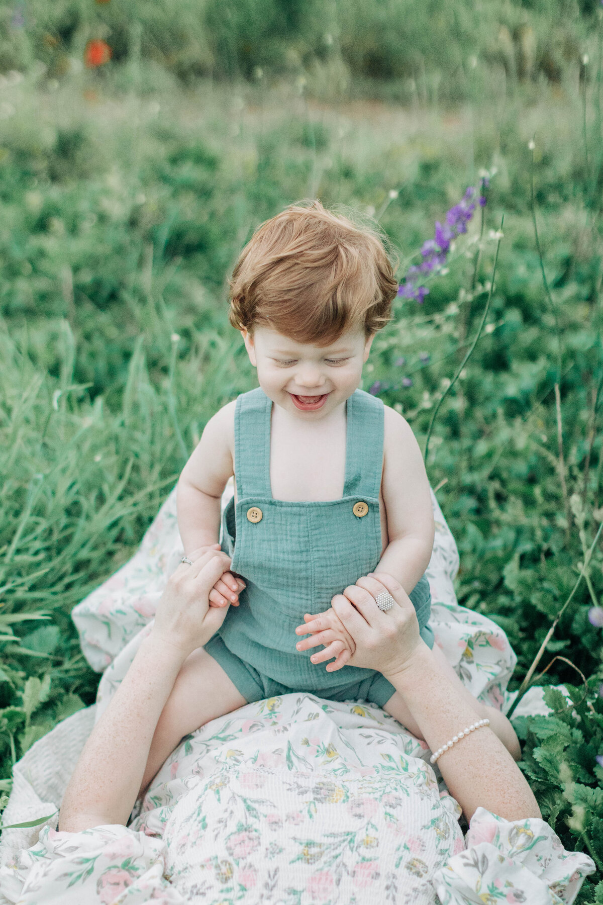 little boy sitting on mom in a field of flowers