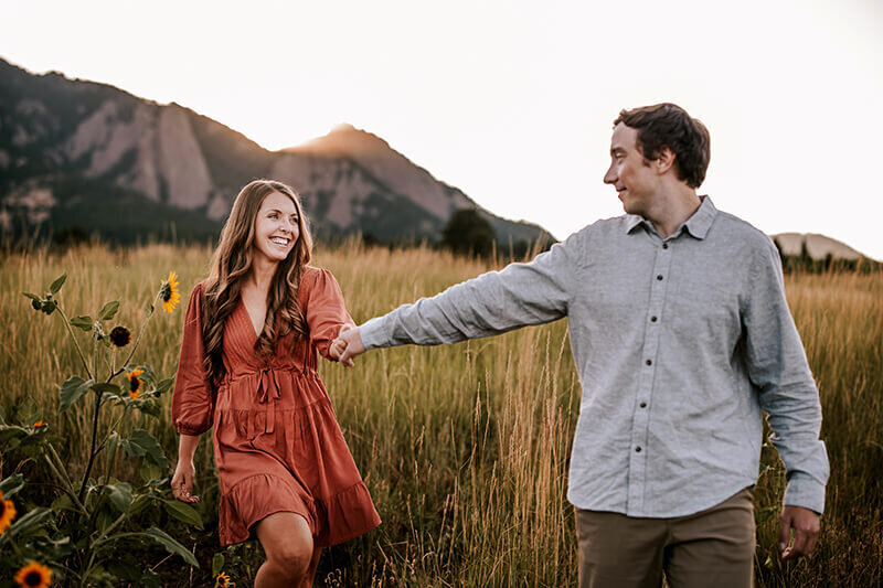 Husband guides wife walking through a grassy field