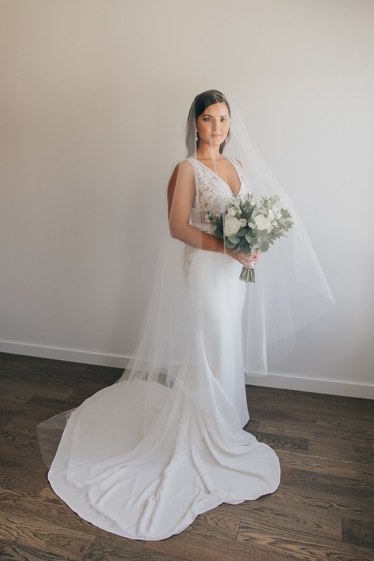 Elegant bride posing in her white wedding dress while holding her white wedding bouquet