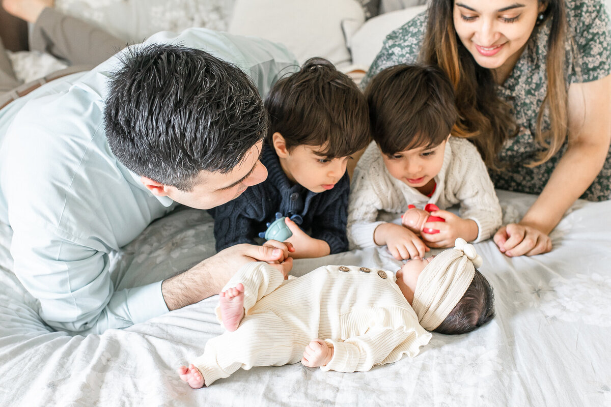 A joyful family welcomes their newborn with love – captured by a Birmingham newborn photographer. Big brothers excitedly gather around their baby sister, as mom and dad share a moment of warmth and connection during this lifestyle newborn session at home.