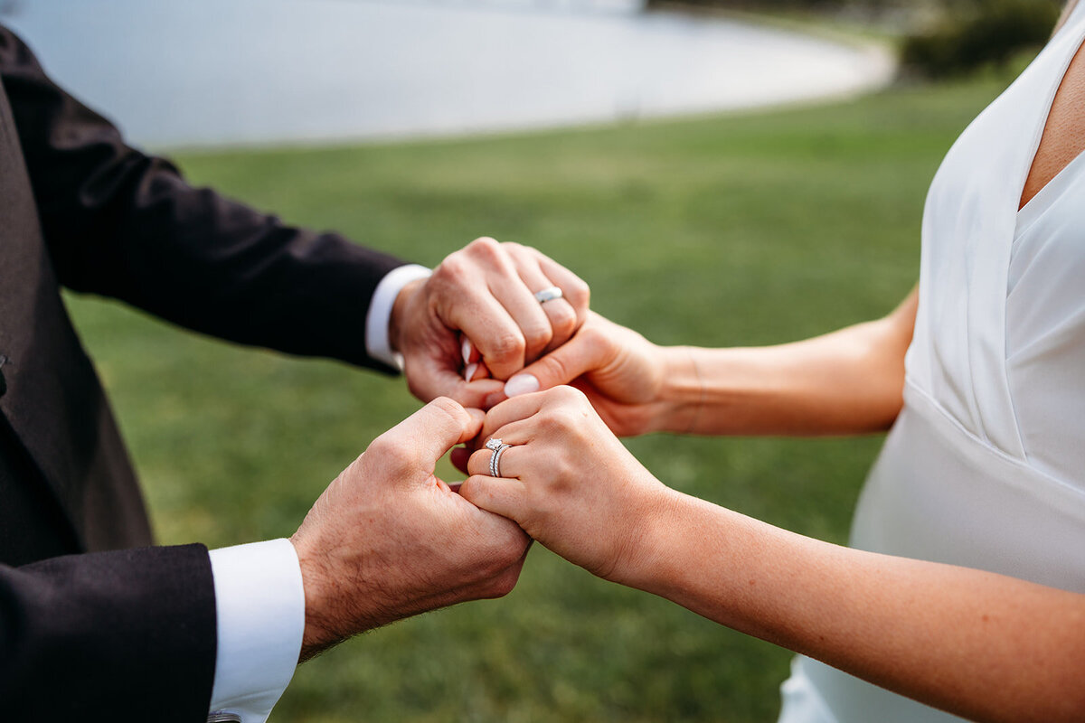 Close of wedding rings as bride and groom hold hands