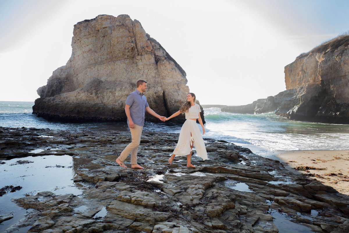 Engagement session on beach, couple holding hands and walking with deneffe studios