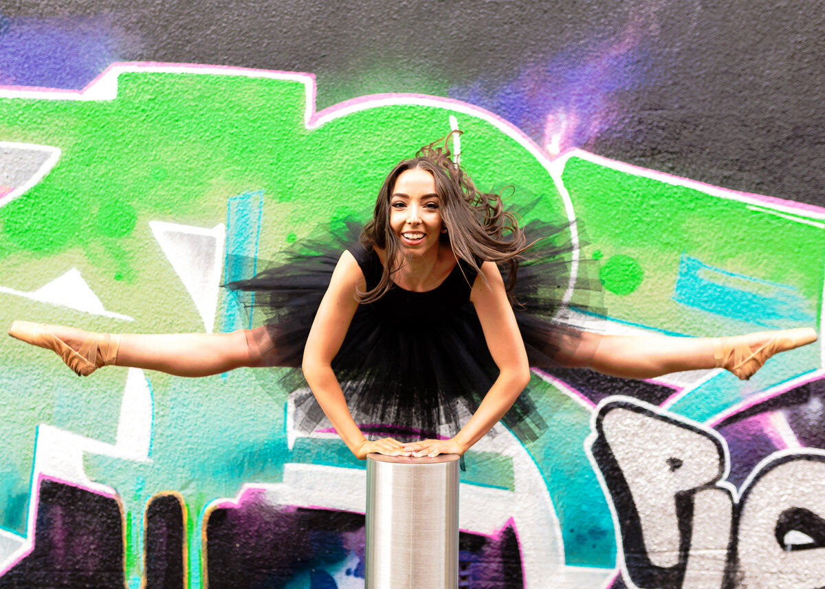 Dancer in tutu doing jump splits near Canberra graffiti wall