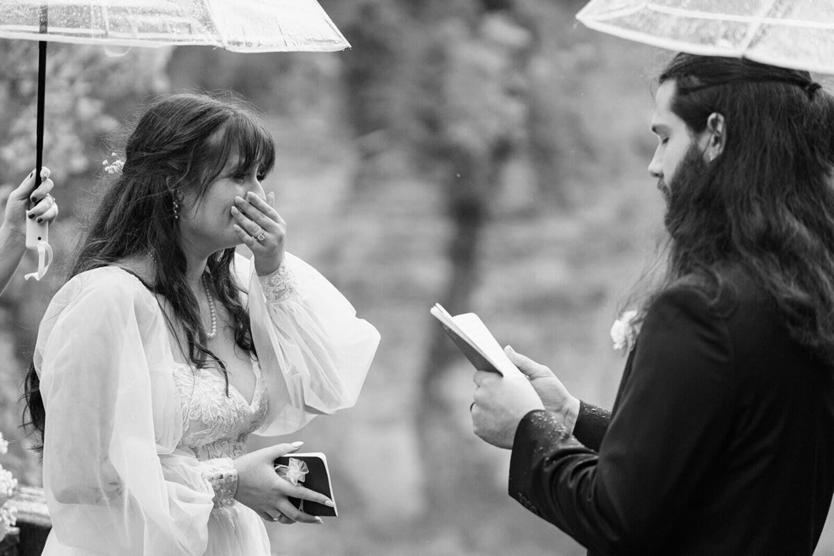 Groom reading vows to bride as she has a hand over her mouth