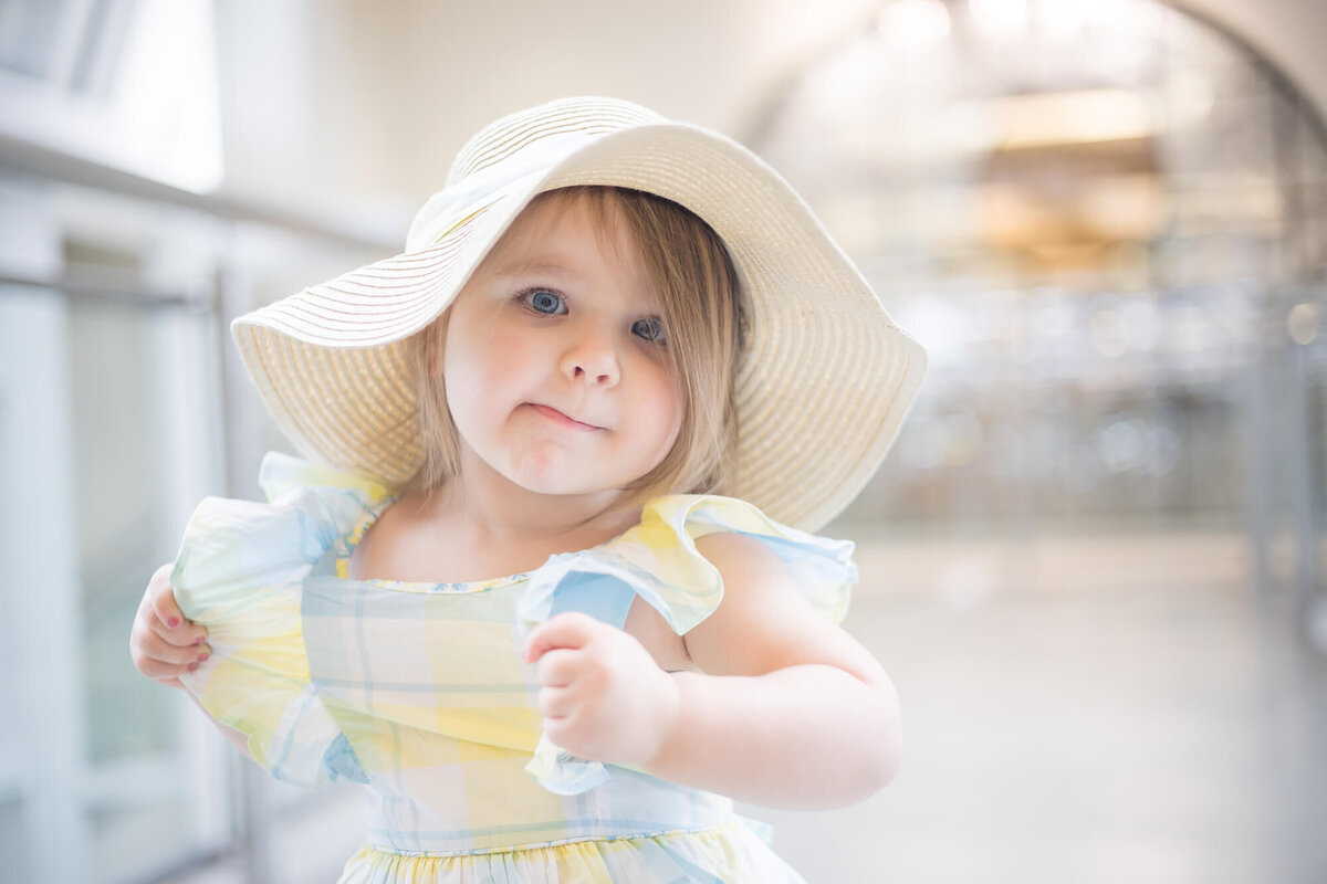 Toddler girl standing on a bridge making a silly face while pulling on her dress