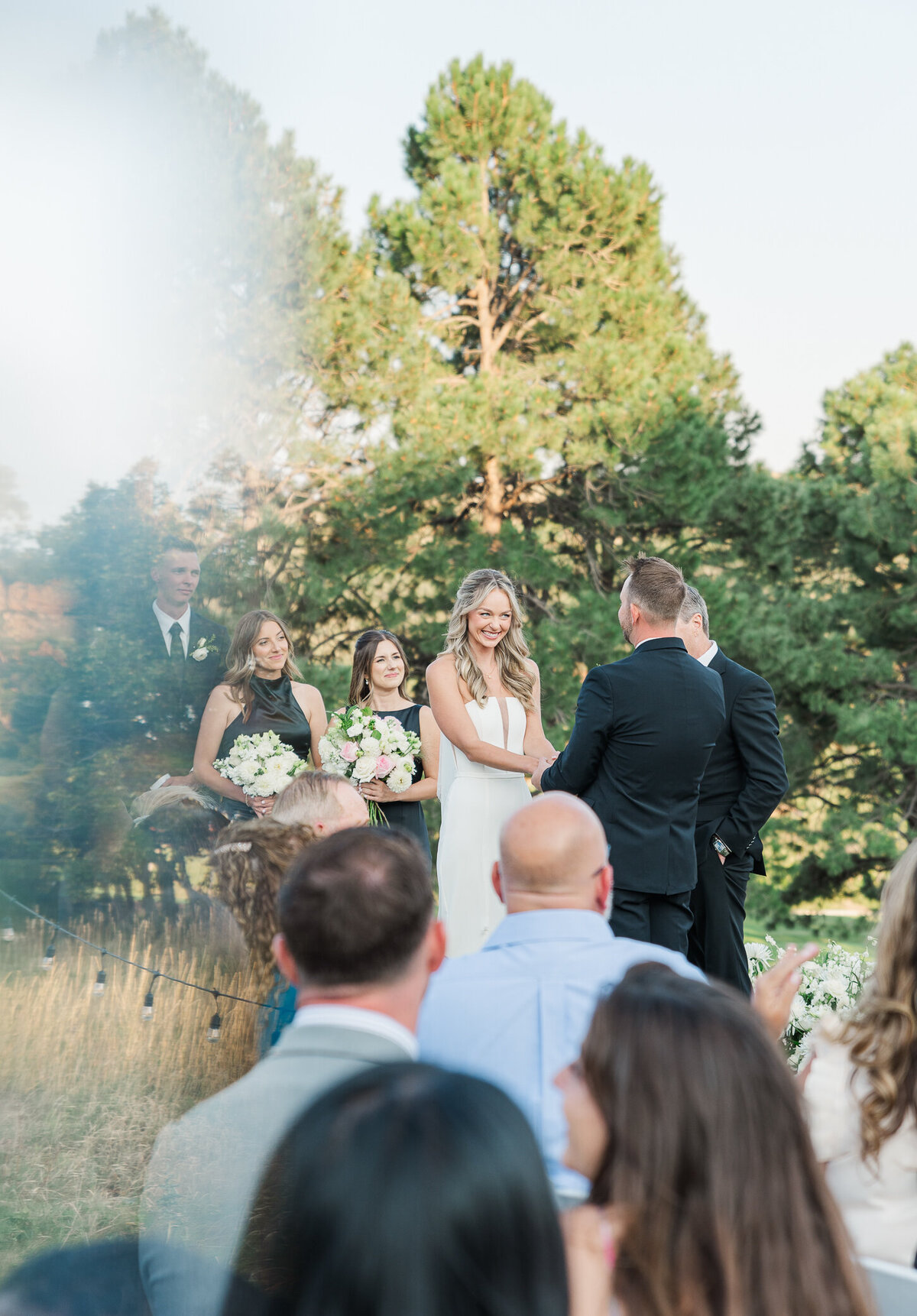 Denver wedding photographer captures a bride smiling at her groom while holding hands at the wedding reception