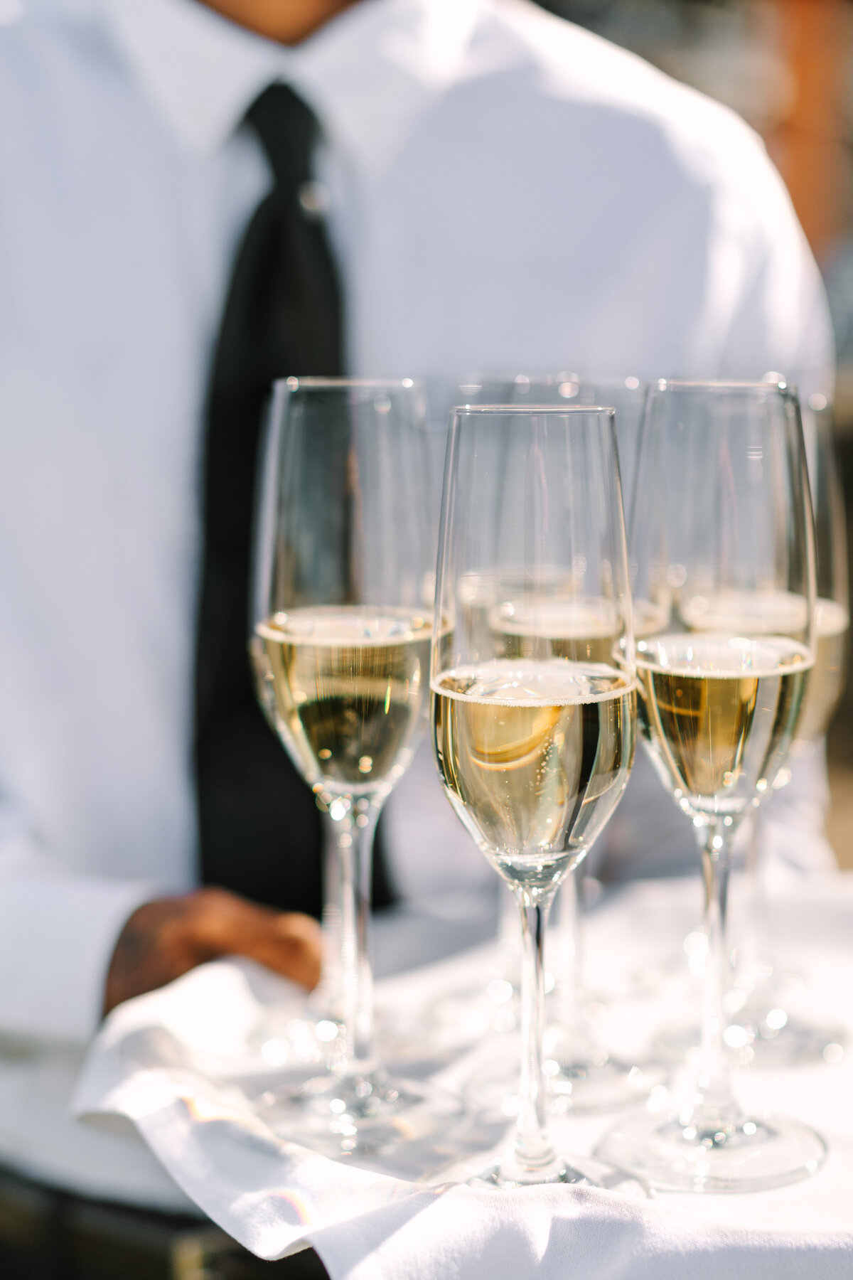 waiter holding tray of champagne in tall glasses.