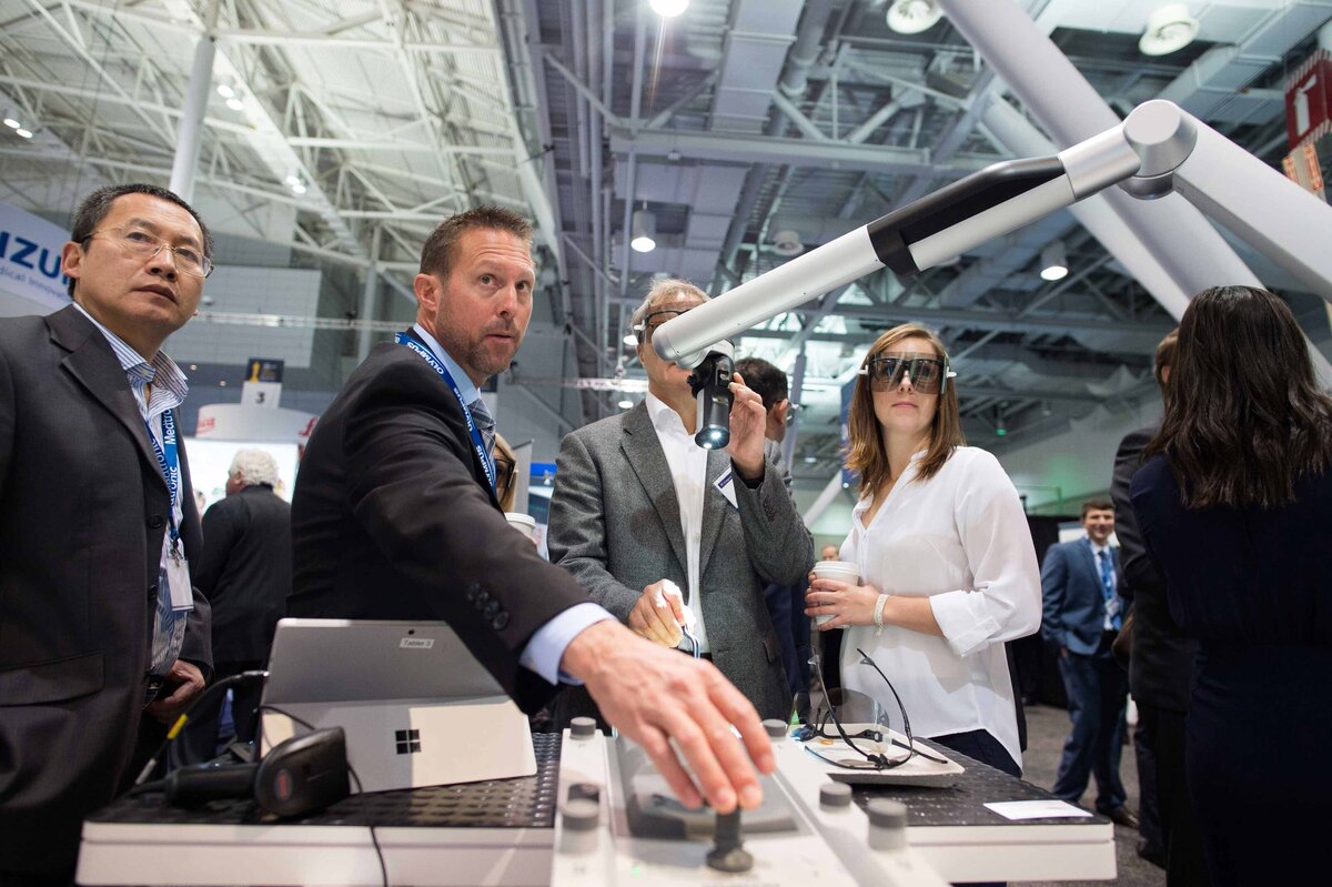 neurosurgeons wear 3D glasses while trying out a microscope at a tradeshow
