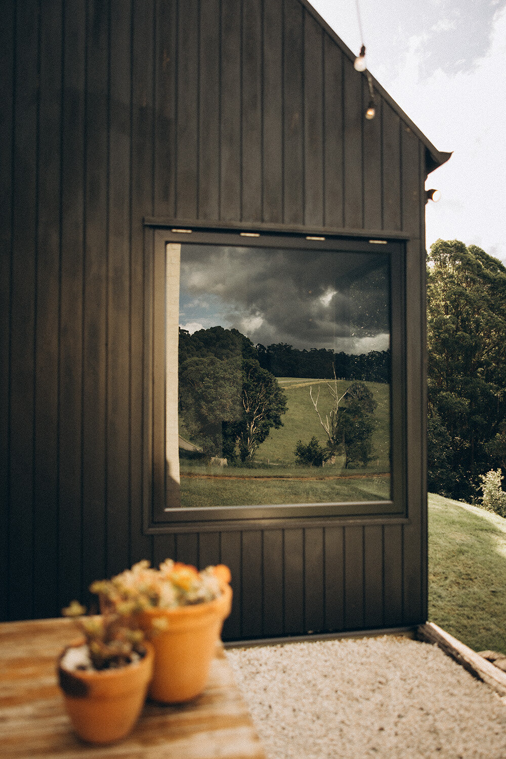 Cretaive reflection on window of the noosa hinterland , with rolling green hills in a bespoke airbnb called Round Hill Retreat. Captured by Sunshine Coast Photographer