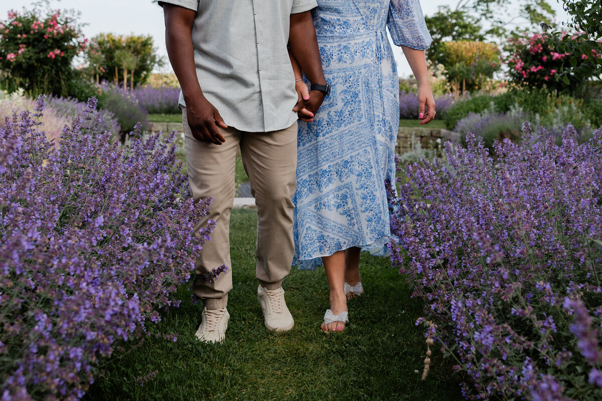 A couple walks through the flowers during their engagement photos.