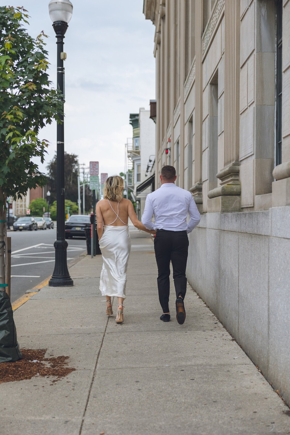 Couple walking casually down a tree-lined sidewalk in Ridgewood.
