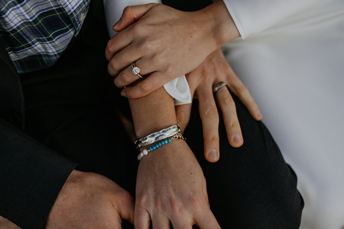 close up of bride and grooms hands and jewelry