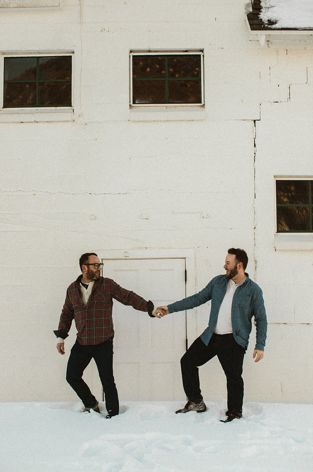 two men hold hands in front of white wall in park city utah