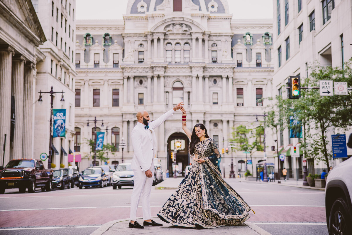 Groom twirling bride during their indian wedding reception on broad st in front of the philadelphia city hall