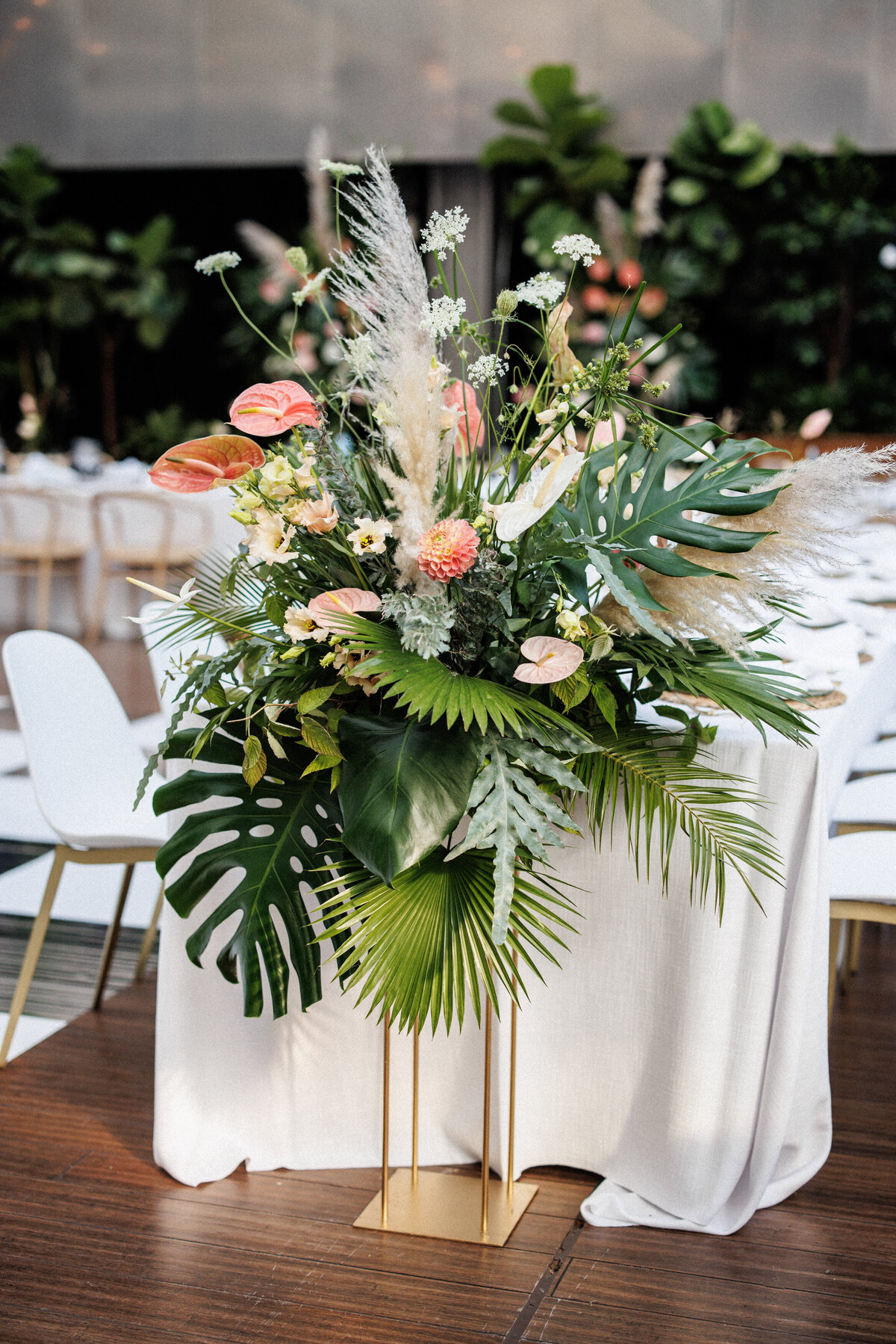 A large floral arrangement with exotic greenery frames a table at a Cathcart wedding reception.