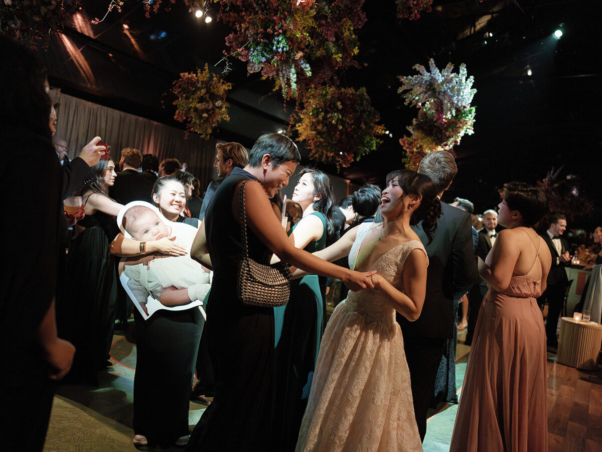 Interacting and sculptural floral clouds hang over the dance floor and bars of this fall wedding reception in Tennessee. Clear top tent build out for fall wedding reception in Tennessee hills.  Product clustered floral clouds in a tasteful fall color palette of copper, ruby, gold, burgundy, rust, and lavender. Orchids, bittersweet berries, butterfly ranunculus, and tulips are highlighted. Unique floral design with flower forward large scale installations. Design by Rosemary & Finch Floral Design in Nashville, TN.