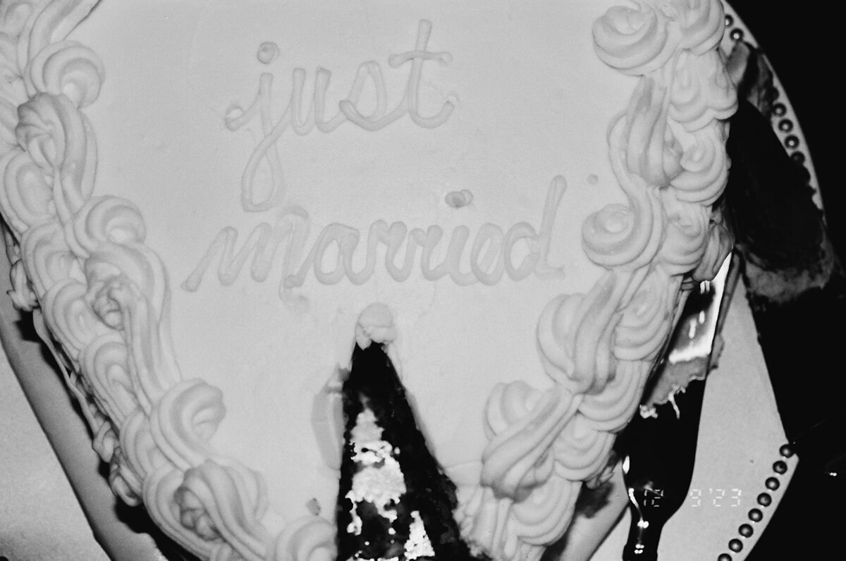 Black and white film picture of a wedding cake with a slice cut out.