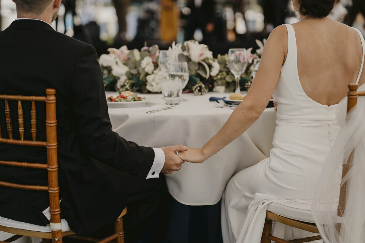 Bride and groom holding hands under the table