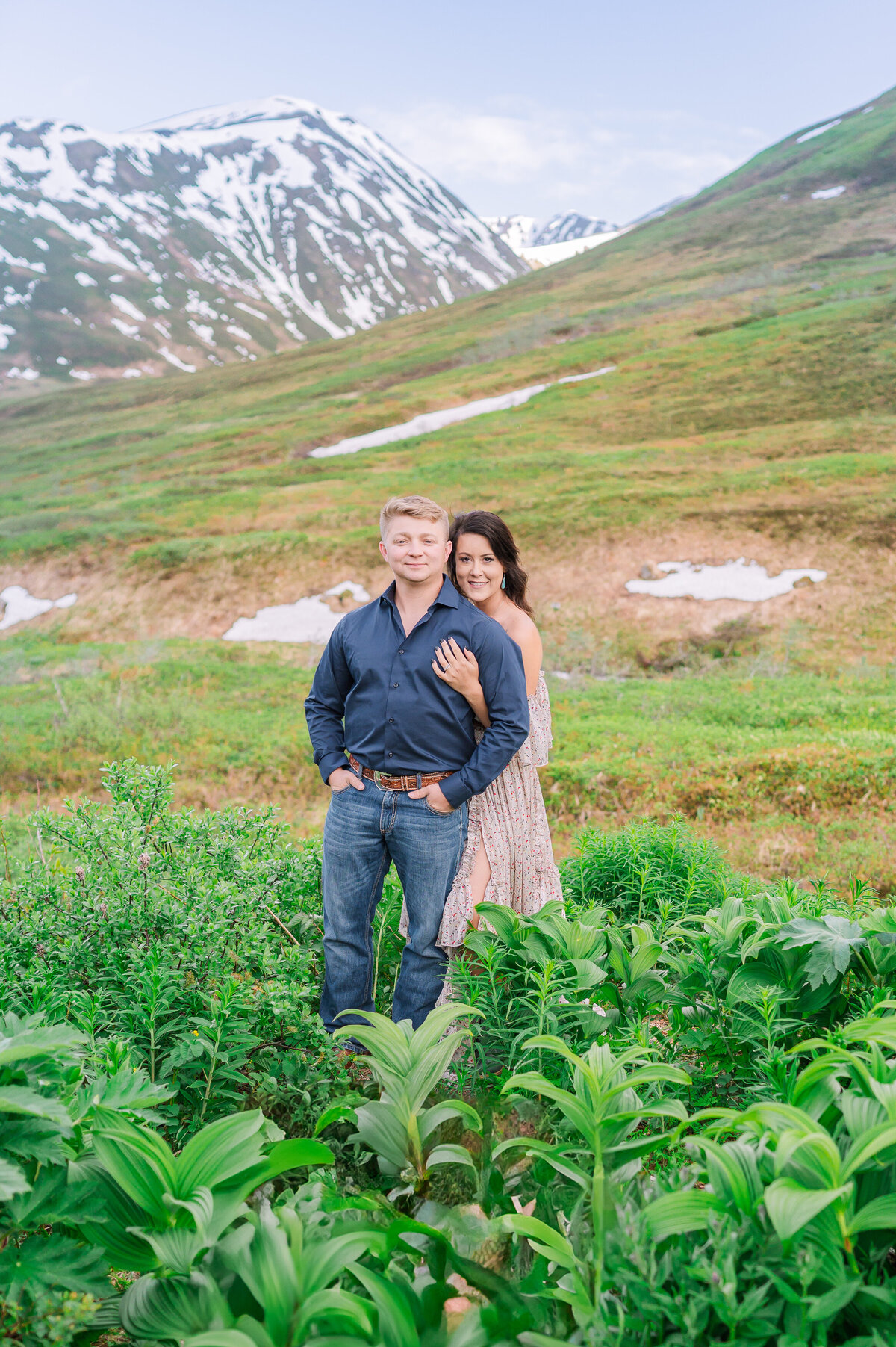 A happy engaged couple hugging at Hatcher's Pass during the midnight sun enjoying their destination wedding photography session with JoLynn Photography