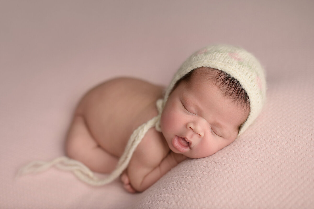 Sleeping newborn baby girl wearing a floral bonnet