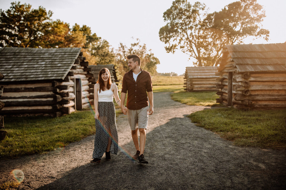 Bride and groom holding hands looking at each other while standing in front of rolling hills with the sunlight coming down on them