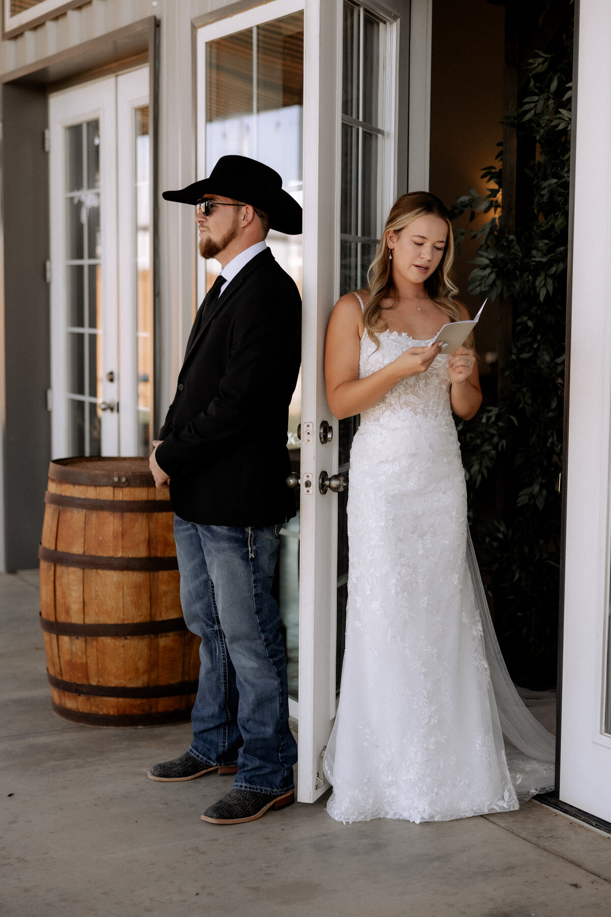 bride and groom standing back to back reading vows to each other