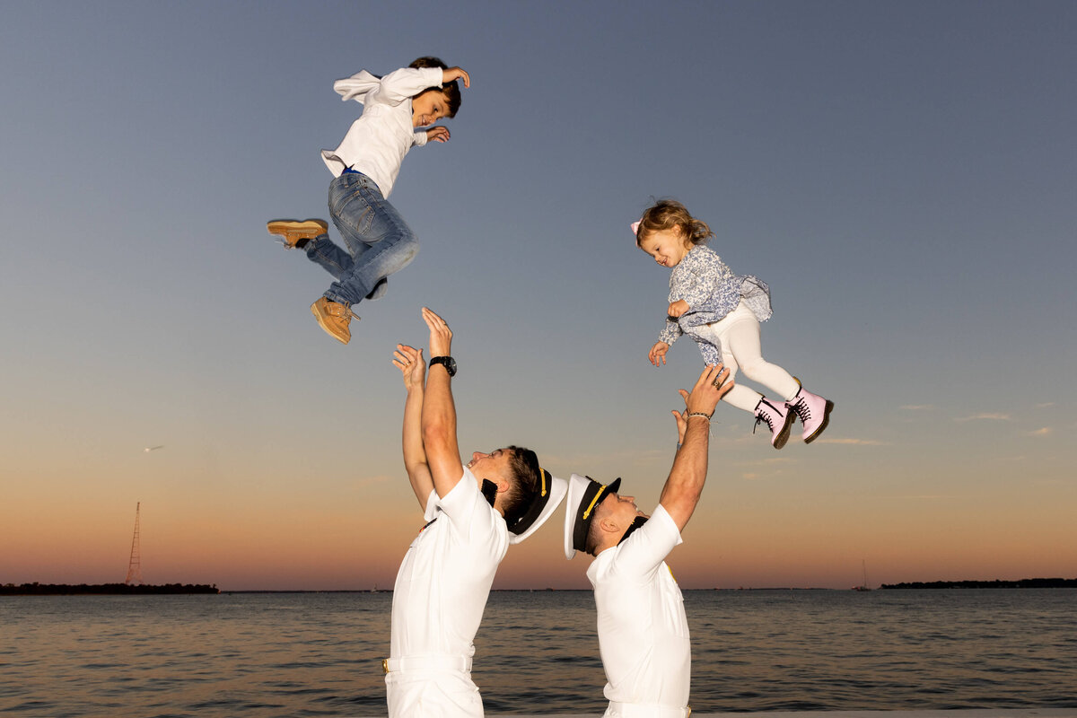 Two Midshipman play catch cute sponsor family kids on the sea wall at Sunset at the USNA in Annapolis, Md.