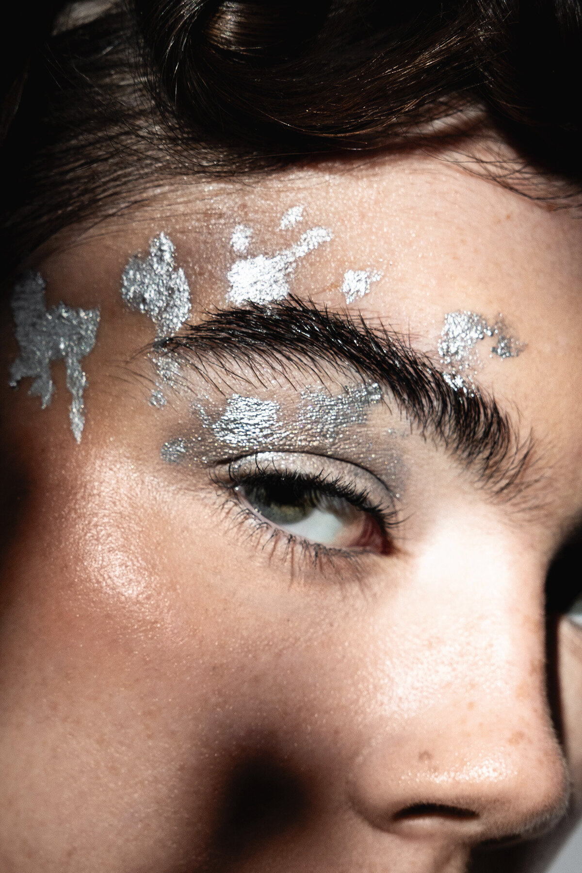 Beauty photography close-up of eye surronded by artistic silver makeup