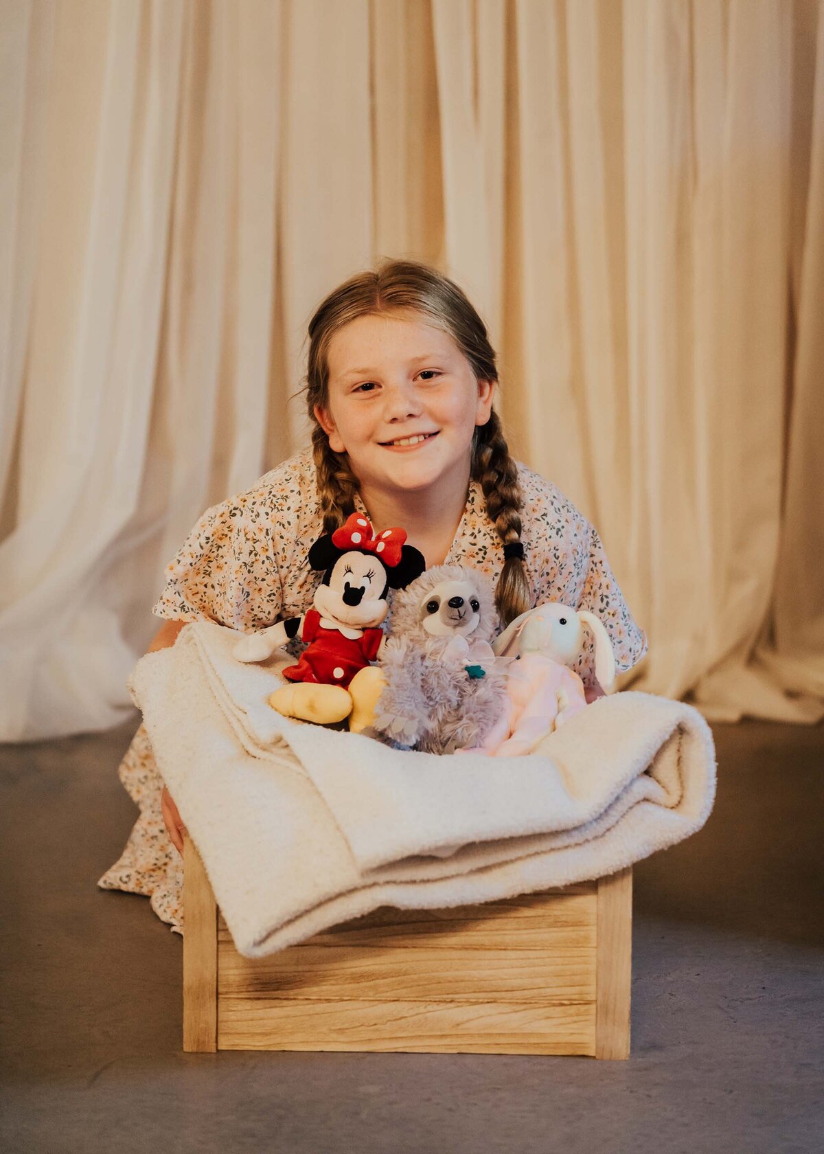 Maddie Rae Photography little girl sitting behind a bucket of stuffed animals smiling at the camera